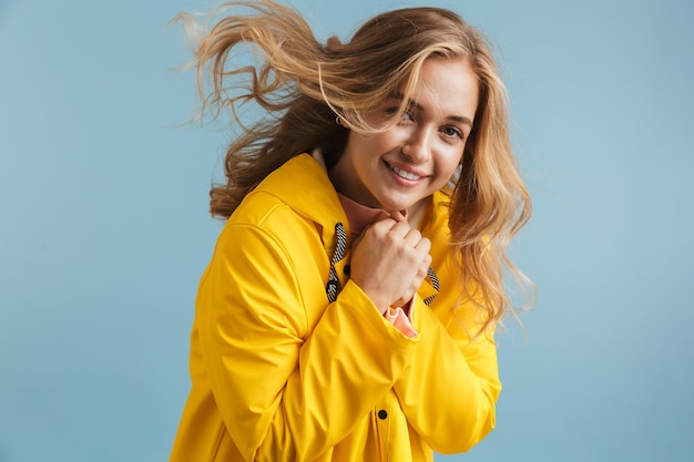 Obraz 20s blond kobieta ubrana w żółty płaszcz, uśmiechając się i patrząc