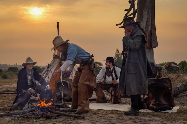 Obraz akcji w stylu vintage grupy kowbojskiej Usiądź wygodnie i zrelaksuj się i napij się kawy o poranku na kempingu w złotym świetle porannego słońca