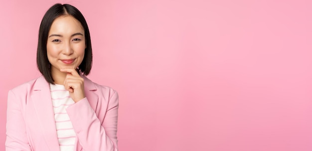 Obraz Azjatyckiej Bizneswoman Stojącej W Myślącej Pozie Podczas Burzy Mózgów W Garniturze Koreańska Sprzedawczyni Przedsiębiorca Pozuje Na Różowym Tle