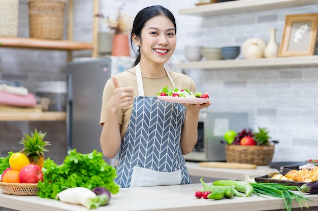 Obraz azjatyckiej kobiety przygotowującej sałatkę w kuchni