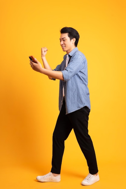 Obraz całego ciała azjatyckiego mężczyzny pozowanie na żółtym tle