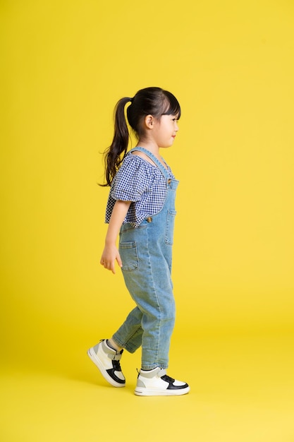 Obraz całego ciała pięknej azjatyckiej dziewczynki na żółtym tle