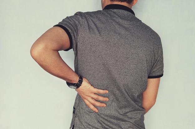 Obraz człowieka cierpiącego na ból pleców na niebieskim tle pacjent z niewydolnością nerek trzyma rękę za plecami artroza chondroza osteoporoza ból mięśni i stawów