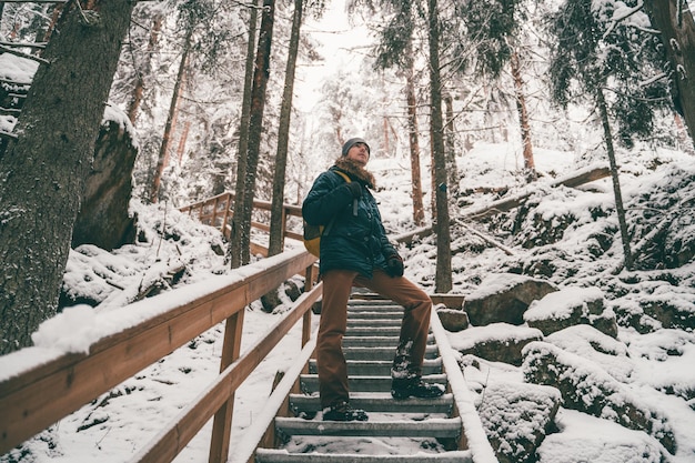 Obraz człowieka w zimowym lesie na drewnianym moście