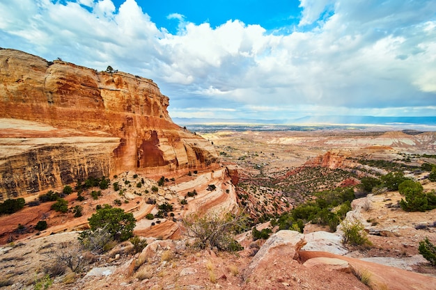 Obraz dużych czerwonych klifów w pustynnym kanionie z otwartą doliną i chmurami