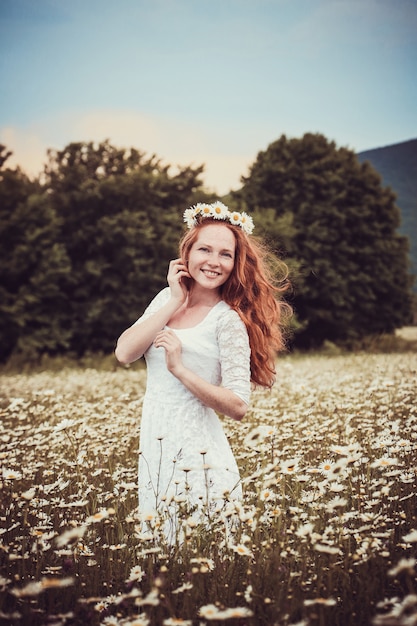 Obraz ładnej kobiety leżącej na polu rumianku, szczęśliwa kobieta trzyma w ręku piękny biały kwiat, wesoła dziewczyna spoczywa na łące stokrotka, relaks na świeżym powietrzu na wiosnę, koncepcja wakacje