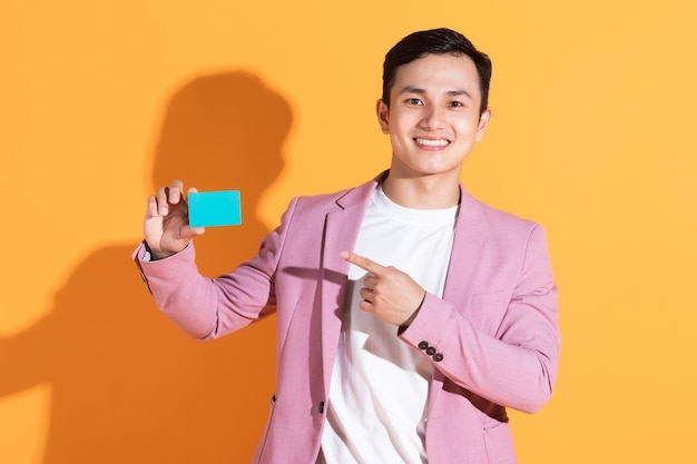 Obraz młodego azjatyckiego mężczyzny trzymającego kartę bankomatową w tle