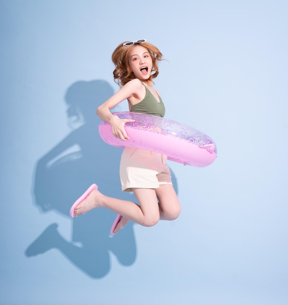 Obraz młodej azjatyckiej dziewczyny trzymającej pływak na niebieskim tle koncepcji wakacji letnich