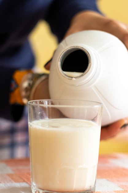 Zdjęcie obraz nierozpoznawalnej osoby nalewającej mleko do szklanki