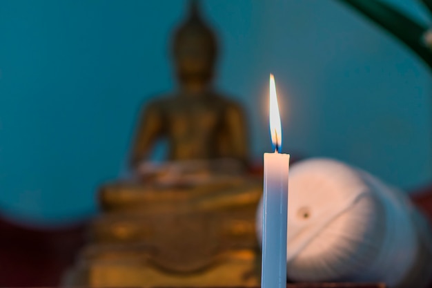 Zdjęcie obraz ostrości świeca świecąca na pierwszym planie i rozmycie tła obrazu buddy.