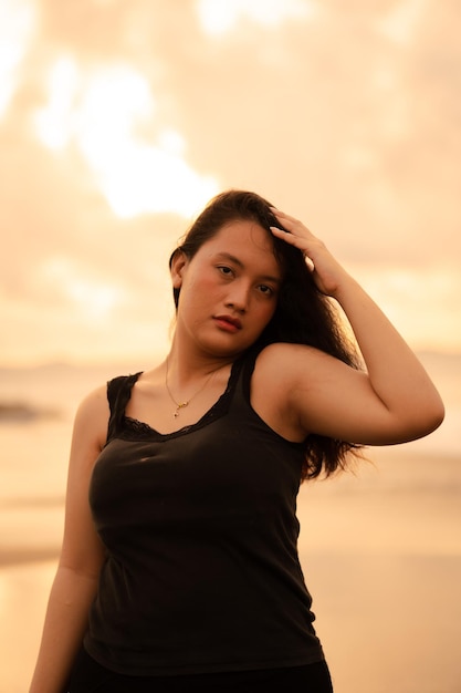 Obraz portretowy azjatyckiej kobiety o czarnych włosach robi bardzo piękną seksowną pozę na plaży
