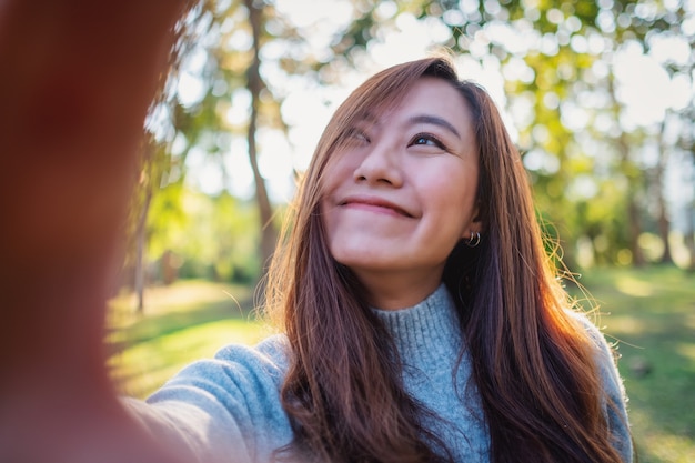 Obraz portretowy szczęśliwej pięknej azjatyckiej kobiety robiącej zdjęcie selfie w parku