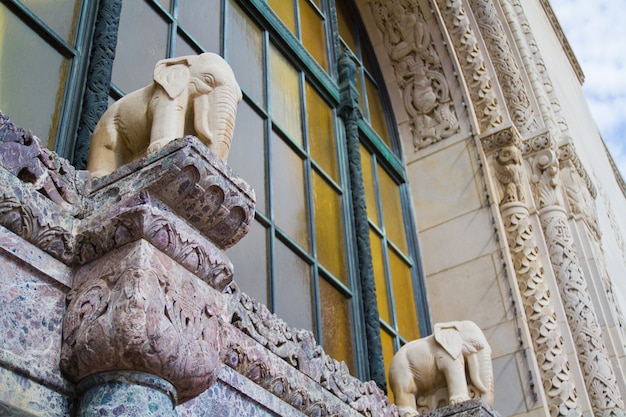 Obraz przedstawiający budynek Lansing z posągami białych słoni umieszczonymi za zardzewiałym oknem