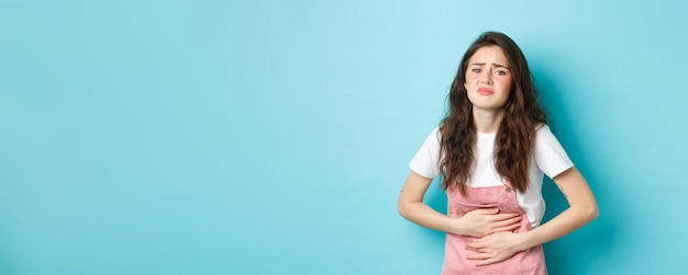 Obraz smutnej młodej kobiety marszczącej brwi trzymającej ręce na brzuchu z bólem bolesne skurcze menstruacyjne stan