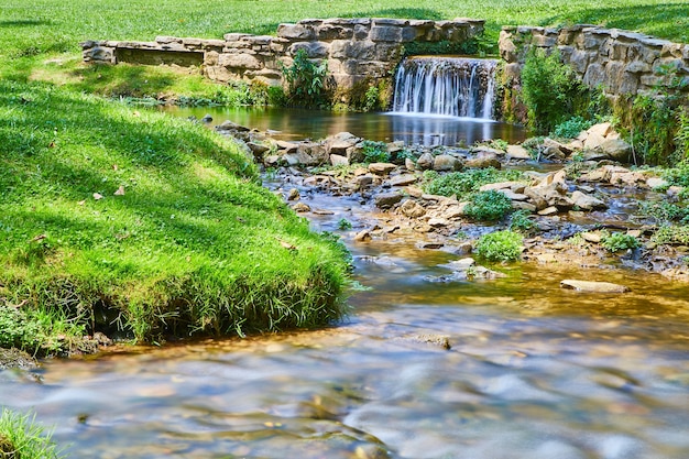 Obraz spokojnego i małego wodospadu z kamiennymi ścianami w płytkiej rzece lub potoku