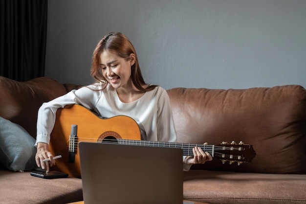 Obraz szczęśliwej pięknej kobiety grającej na gitarze i komponującej piosenkę