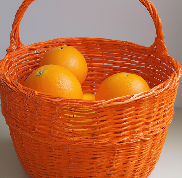 Obraz z bliska sterty pomarańczy w tradycyjnym wiklinowym koszu na szarym tle
