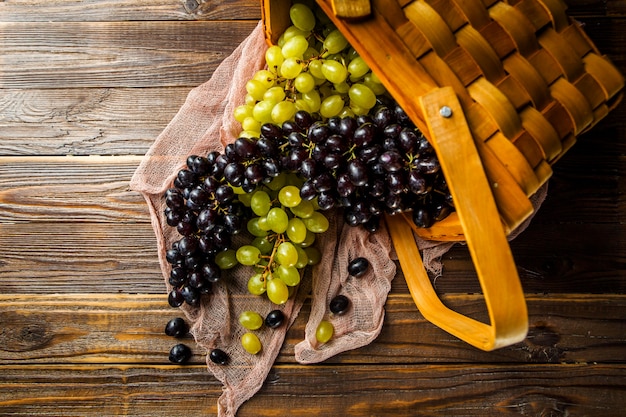 Obrazek winogrona zielenieje i czerń w drewnianym koszu na stole