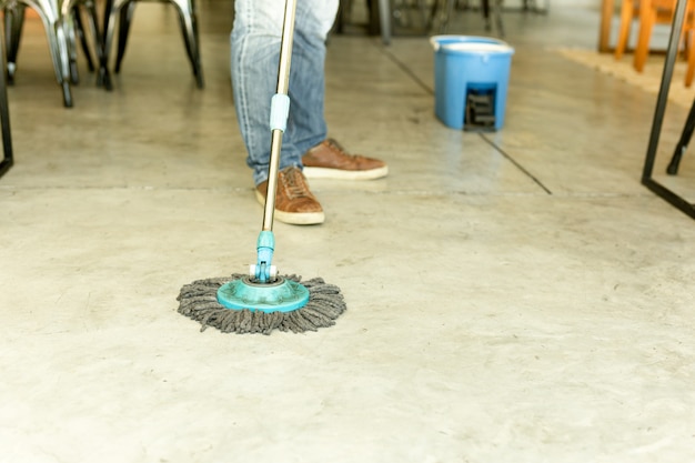 Obsługuje pracownika z kwacza i wiadra cleaning podłoga w kawiarni.