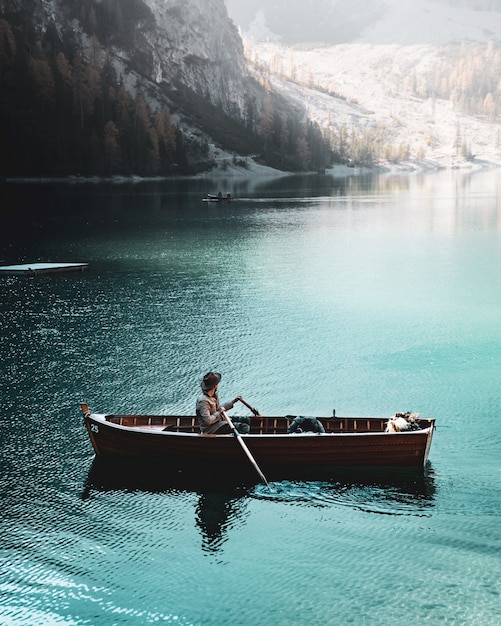 Obsługuje wioślarską łódź w błękitnym jeziorze Braies w dolomitach, Południowy Tyrol, Włochy.