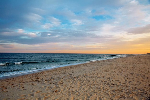 Ocean niebo fala piasek i plaża z zachodem słońca