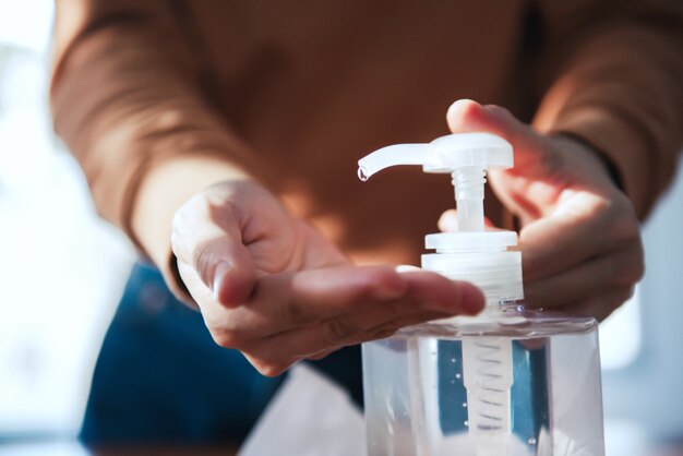Ochrona przed wirusem Corona, Zbliżenie myje ręce żelami dezynfekującymi, Kobieta w kwarantannie dla koronawirusa w masce ochronnej, Pracująca w domu.