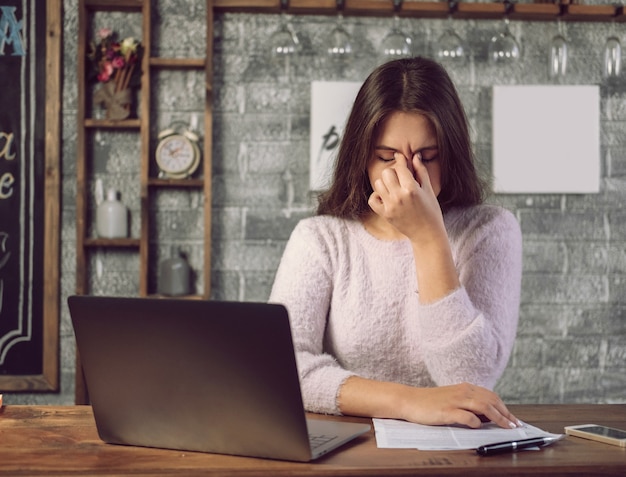 Oczy bolą przy pracy na laptopie, dziewczyna przeciera oczy