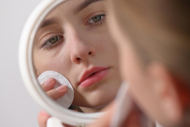 Zdjęcie odbicie kobiety nakładającej makijaż w lustrze