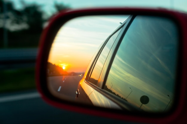 Odbicie zachodu słońca w lusterku wstecznym samochodu na autostradzie Rozmycie zdjęcia