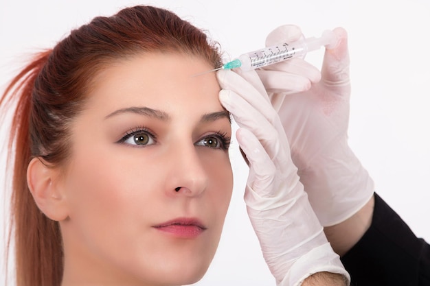 Zdjęcie odcięte ręce kosmetykki wstrzykującej botox na czoło kobiety w spa