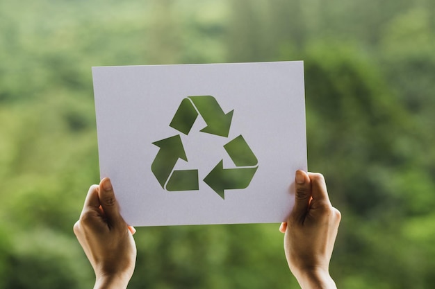 Odcięte ręce osoby trzymającej papier z symbolem recyklingu