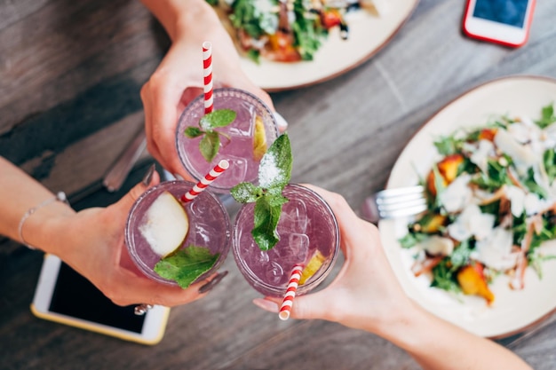 Odcięte ręce przyjaciół pijących na stole w restauracji.
