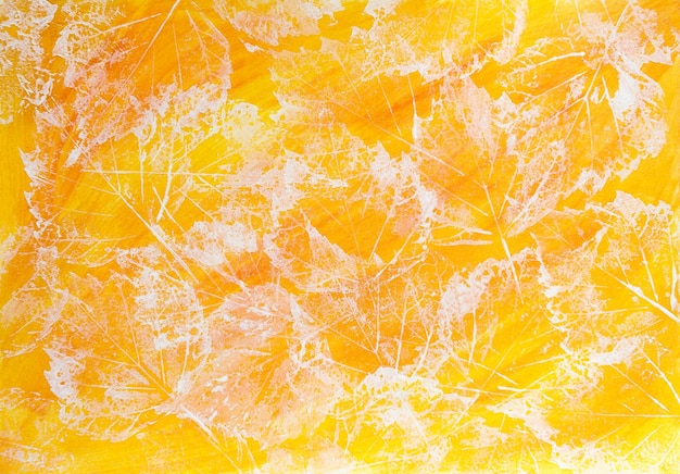 Zdjęcie odciski jesiennych liści na żółtym tle. tekstura wykonana białą farbą akrylową na papierze pomalowanym na żółto