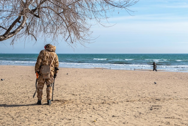 Odessa Ukraina 07022022 Mężczyzna szuka kosztowności za pomocą wykrywacza metalu na plaży Łuzanówka w Odessie na Ukrainie w słoneczny zimowy dzień