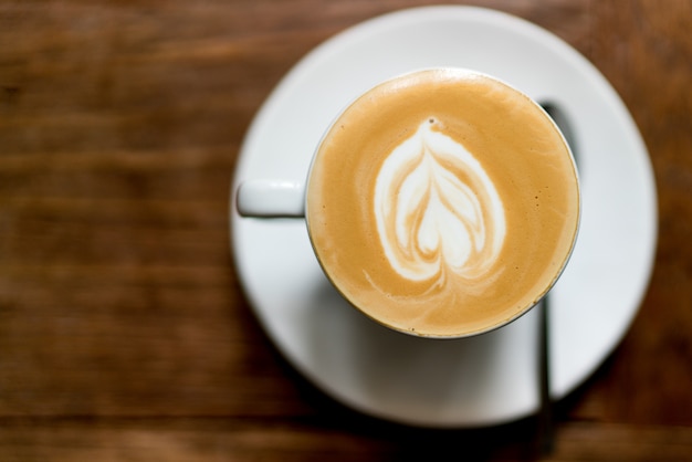 Zdjęcie odgórnego widoku latte sztuki kawa na drewnianym. piankowa latte art w kształcie serca. s.