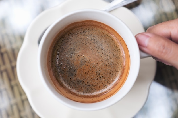 Odgórnego widoku wizerunek trzyma filiżankę gorąca czarna kawa ręka na stole