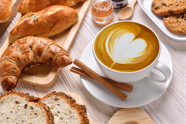 Odgórny Widok Filiżanki Kawy Latte Z Chlebami, Babeczka, Croissant I Piekarnia Na Białym Drewnianym Stole