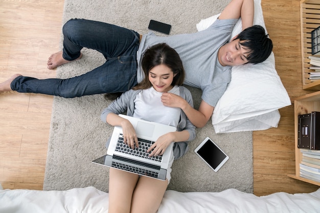 Odgórny widok kochanek używa cyfrowego laptopu dosypianie na Parkietowej podłoga z dywanem przy nowożytnym domem
