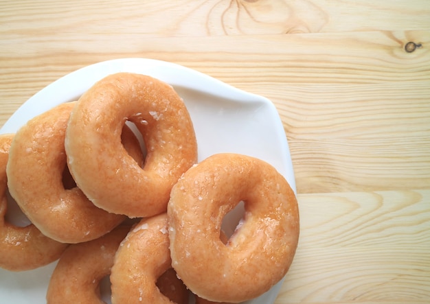 Odgórny widok oszkleni donuts słuzyć na bielu talerzu na drewnianym stole