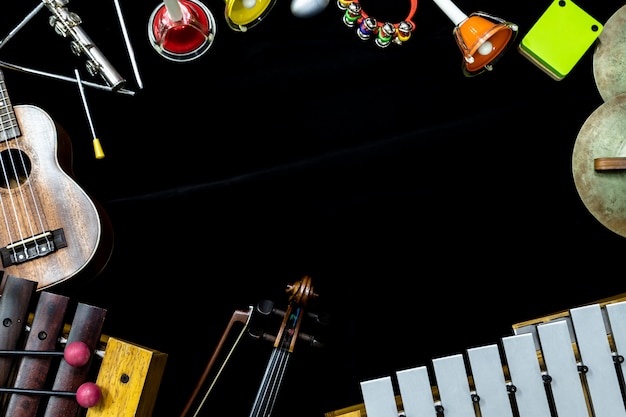 Zdjęcie odgórny widok skrzypcowa gitara i ukulele z instrumentami perkusyjnymi na czarnym tle