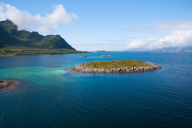Odkryj świat. Rejs dookoła świata. Wyspa kamienista otoczona idylliczną wodą morską w Norwegii. Seascape z norweskimi fiordami na wyspie. Wyspa kamieniste klify wybrzeża. Najlepsze miejsca przyrodnicze do odwiedzenia w Norwegii.