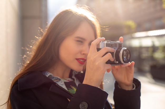 Odkryty jesień uśmiechnięty styl życia portret całkiem młoda kobieta, zabawy w mieście z aparatem, zdjęcie z podróży fotografa. Robienie zdjęć w stylu hipsterskim. Rozbłysk słoneczny