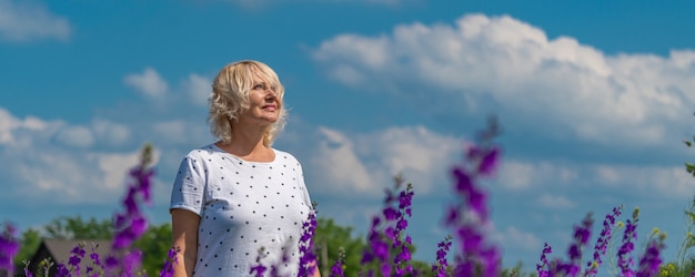 odkryty portret pięknej szczęśliwej blondynki w średnim wieku na polu z kwiatami