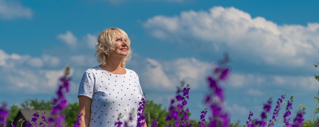 Zdjęcie odkryty portret pięknej szczęśliwej blondynki w średnim wieku na polu z kwiatami