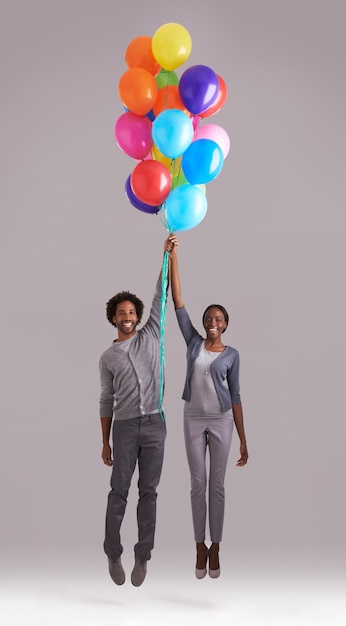 Odlecieć Studio Ujęcie Młodej Pary Trzymającej Pęk Balonów, Gdy Odlatują