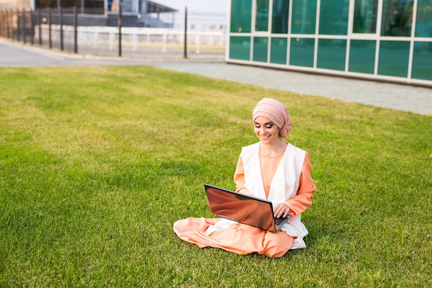 Odnosząca sukcesy arabka i laptop arabska bizneswoman w hidżabie pracująca na laptopie w parku