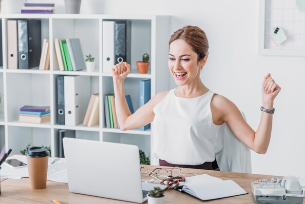 Odnosząca Sukcesy Bizneswoman świętuje W Miejscu Pracy I Patrzy Na Laptopa