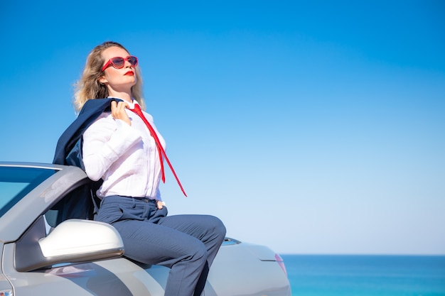 Odnosząca sukcesy młoda bizneswoman na plaży Kobieta siedząca na klasycznym kabriolecie