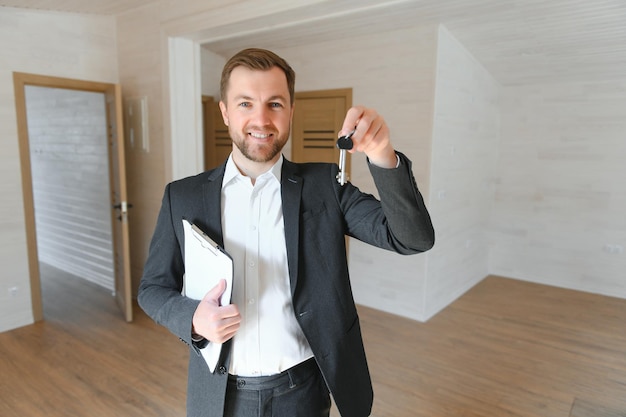 Zdjęcie odnoszący sukcesy agent nieruchomości stoi w nowym budynku modułowym i oferuje nowy dom