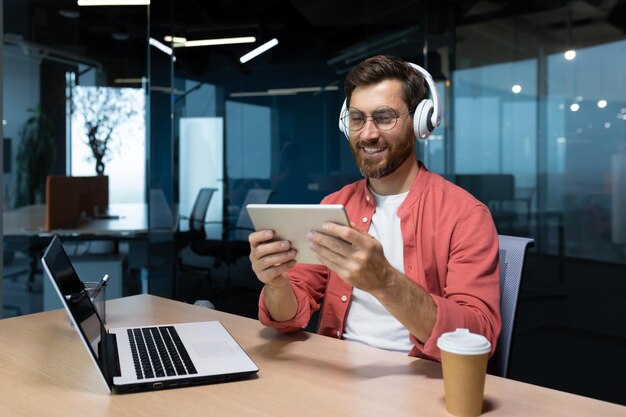 Odnoszący sukcesy biznesmen w miejscu pracy uśmiechnięty mężczyzna oglądający wideo online siedzący przy biurku